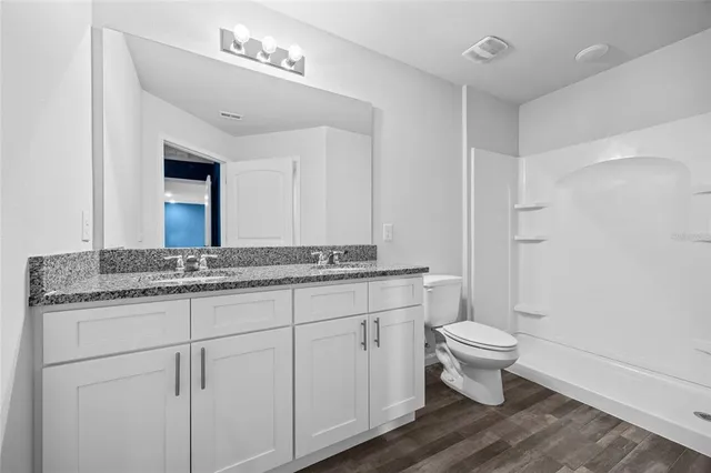 a bathroom with a granite countertop sink a toilet and a mirror