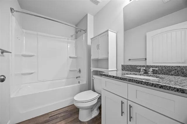 a bathroom with a granite countertop sink a toilet and shower