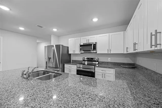 a kitchen with stainless steel appliances granite countertop a sink refrigerator and microwave