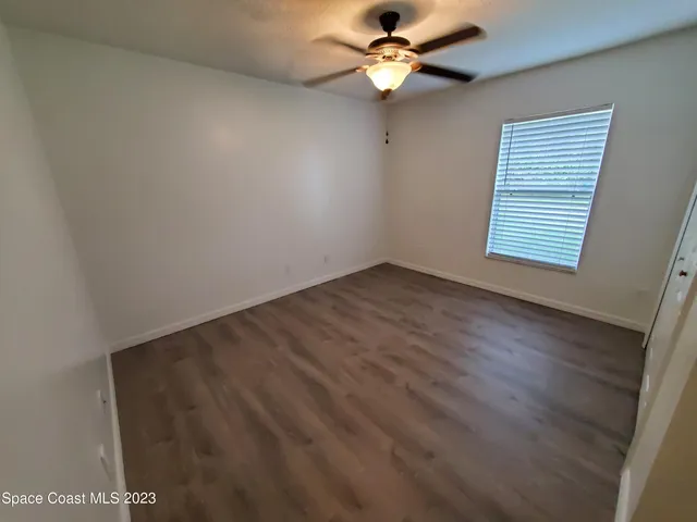 an empty room with a window and a ceiling fan