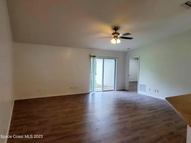 a view of a room with wooden floor and a ceiling fan