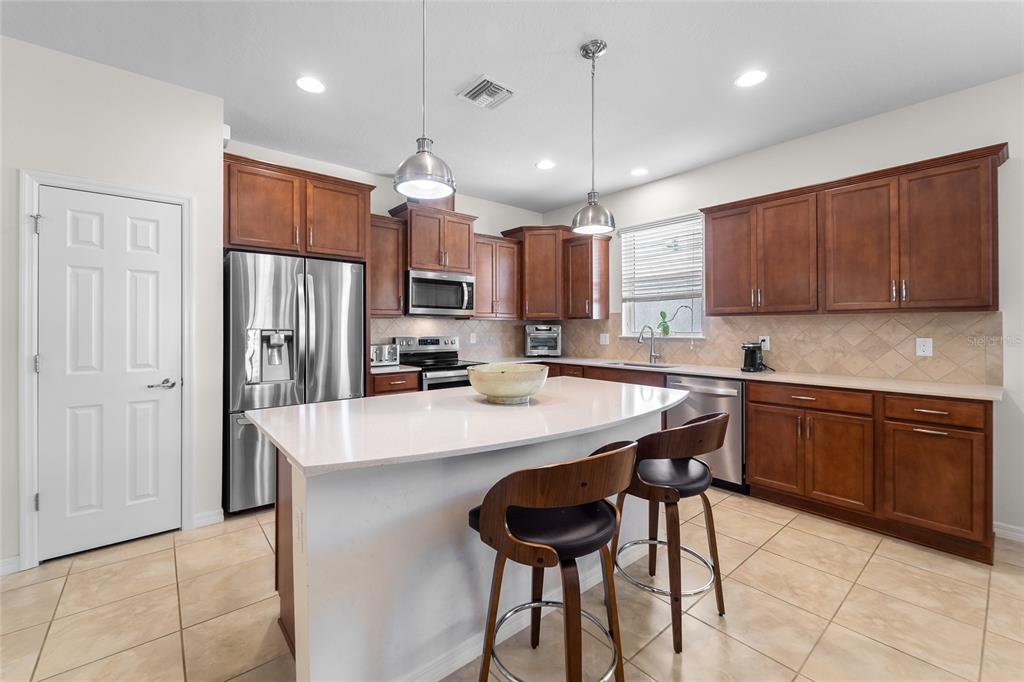 6306 Kenava Loop Palmetto, FL 34221 - Photo 5 of 31 a kitchen with stainless steel appliances granite countertop a refrigerator a sink dishwasher a stove and a refrigerator with wooden floor