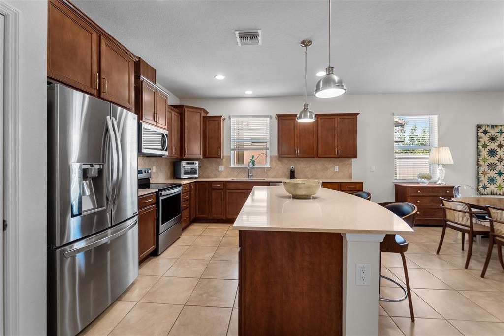 6306 Kenava Loop Palmetto, FL 34221 - Photo 6 of 31 a kitchen with stainless steel appliances granite countertop a refrigerator a sink a stove a dining table and chairs