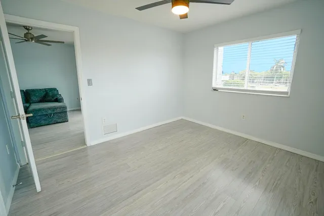 an empty room with wooden floor mirror and windows