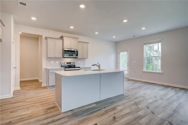 a kitchen with stainless steel appliances granite countertop a stove a sink and a microwave