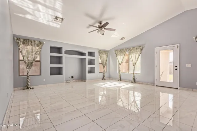 a view of an empty room with a window and kitchen view