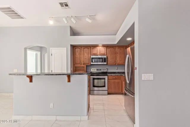 a kitchen with stainless steel appliances granite countertop a refrigerator and a stove top oven