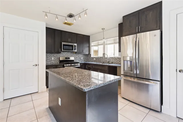 a kitchen with kitchen island a counter top space cabinets and stainless steel appliances
