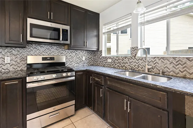 a kitchen with granite countertop cabinets stainless steel appliances a sink and window