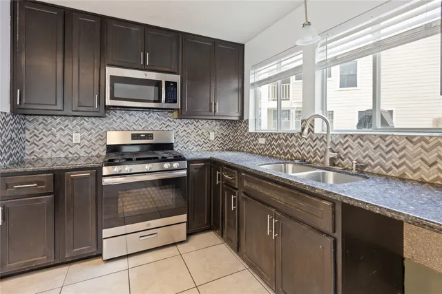 a kitchen with stainless steel appliances granite countertop a sink stove and microwave