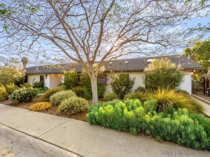 a front view of a house with a yard and potted plants