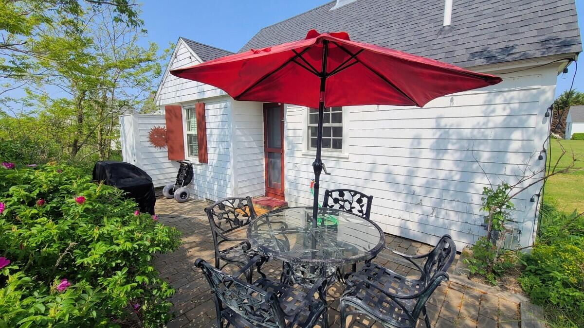 670 Shore Road, Unit 5 Truro, MA 02666 - Photo 4 of 22 a view of a house with backyard sitting area and blue umbrellas