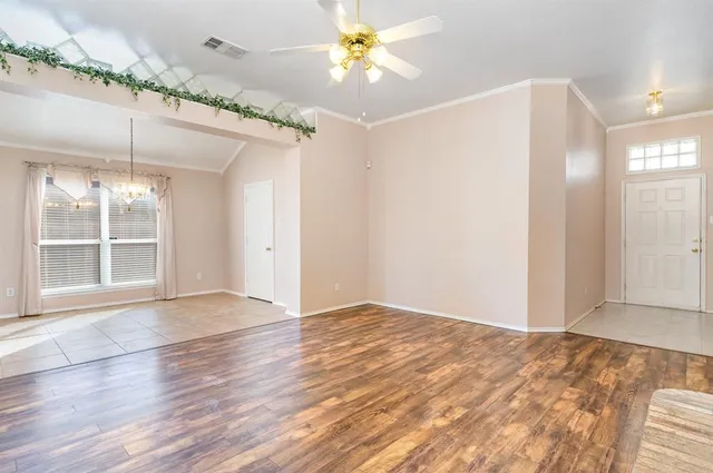 a view of an empty room with window and wooden floor