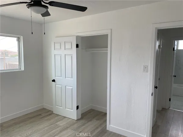 an empty room with wooden floor closet and windows