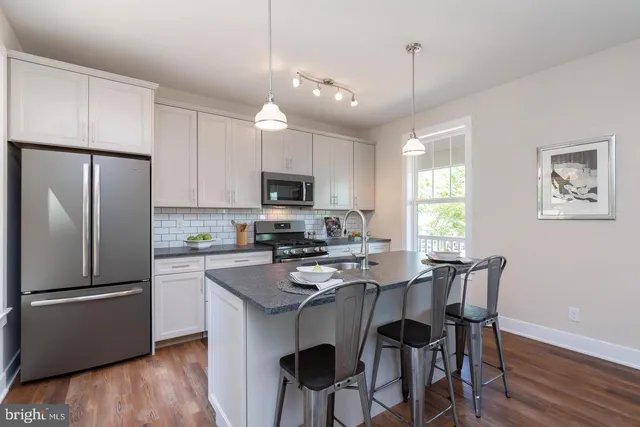 a kitchen with stainless steel appliances a table chairs refrigerator and microwave