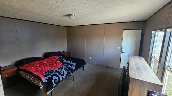 a bedroom with a bed and a potted plant on the dresser