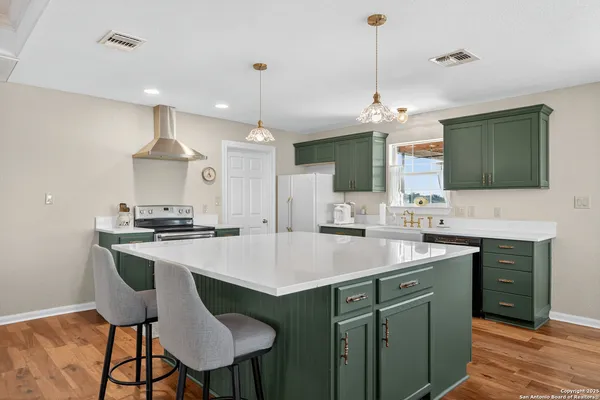 a kitchen with stainless steel appliances granite countertop a sink a stove a refrigerator cabinets and a dining table
