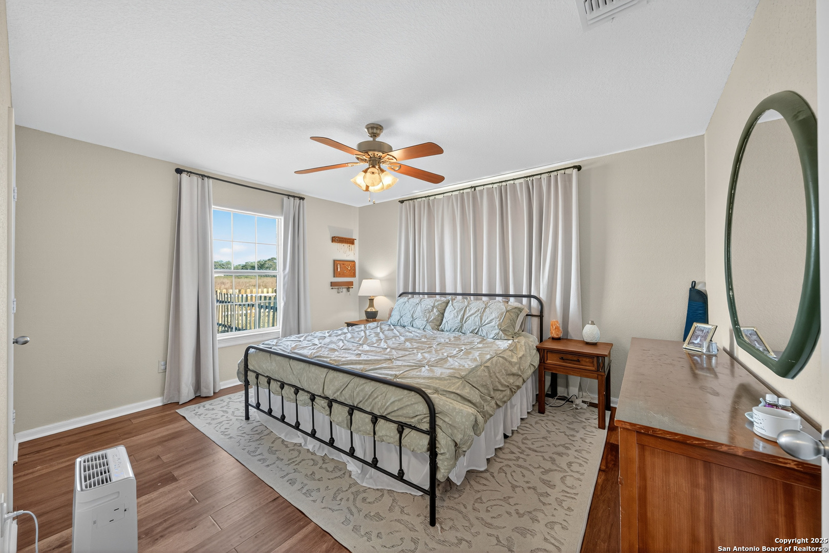 118 Stallion Trail Natalia, TX 78059 - Photo 20 of 35 a bedroom with a bed a mirror on dresser and a wooden floor