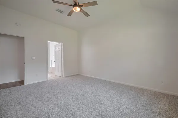 a view of an empty room and chandelier fan