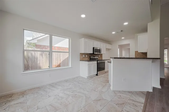 a view of kitchen with granite countertop cabinets and refrigerator