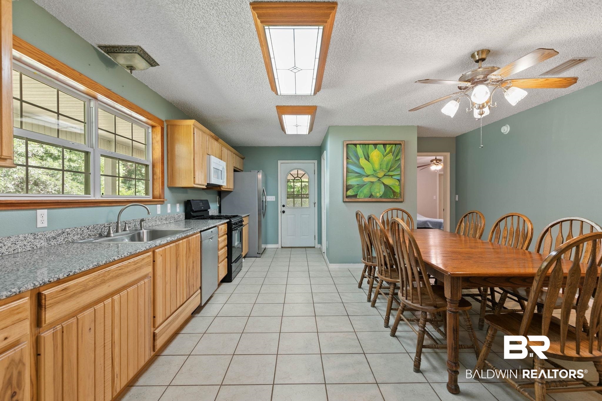 20219 Greek Cemetery Road Robertsdale, AL 36567 - Photo 19 of 41 Kitchen and dining area featuring wood cabinetry, granite-finish countertops, and white square floor tiles