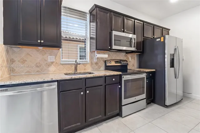a kitchen with stainless steel appliances granite countertop a refrigerator sink and microwave