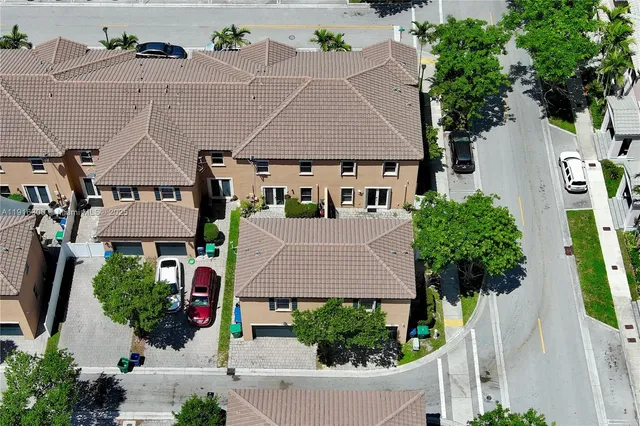 an aerial view of multiple houses with yard and trees