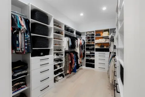 a view of walk in closet with clothes and shoes