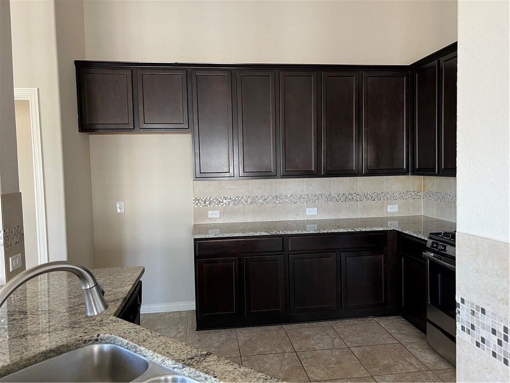 3645 Rams Horn Way Round Rock, TX 78665 - Photo 12 of 16 Kitchen with dark wood finish cabinetry, stainless steel gas stove, and light stone countertops
