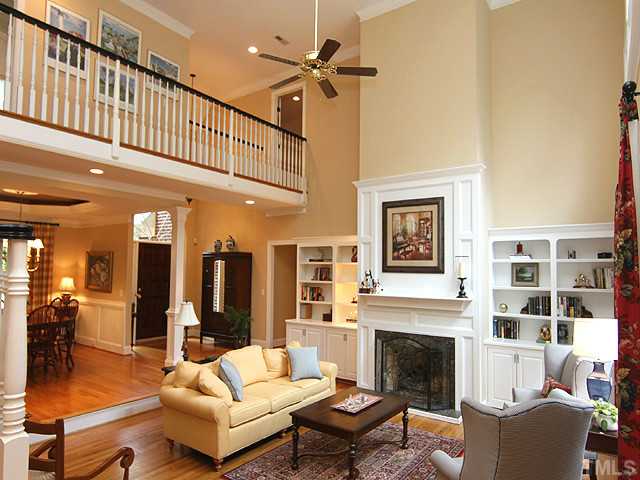 4636 Hidden Harbor Lane Raleigh, NC 27615 - Photo 2 of 16 Living Room with soaring ceiling , built - in shelving, one of two fireplaces, and view of lush back yard