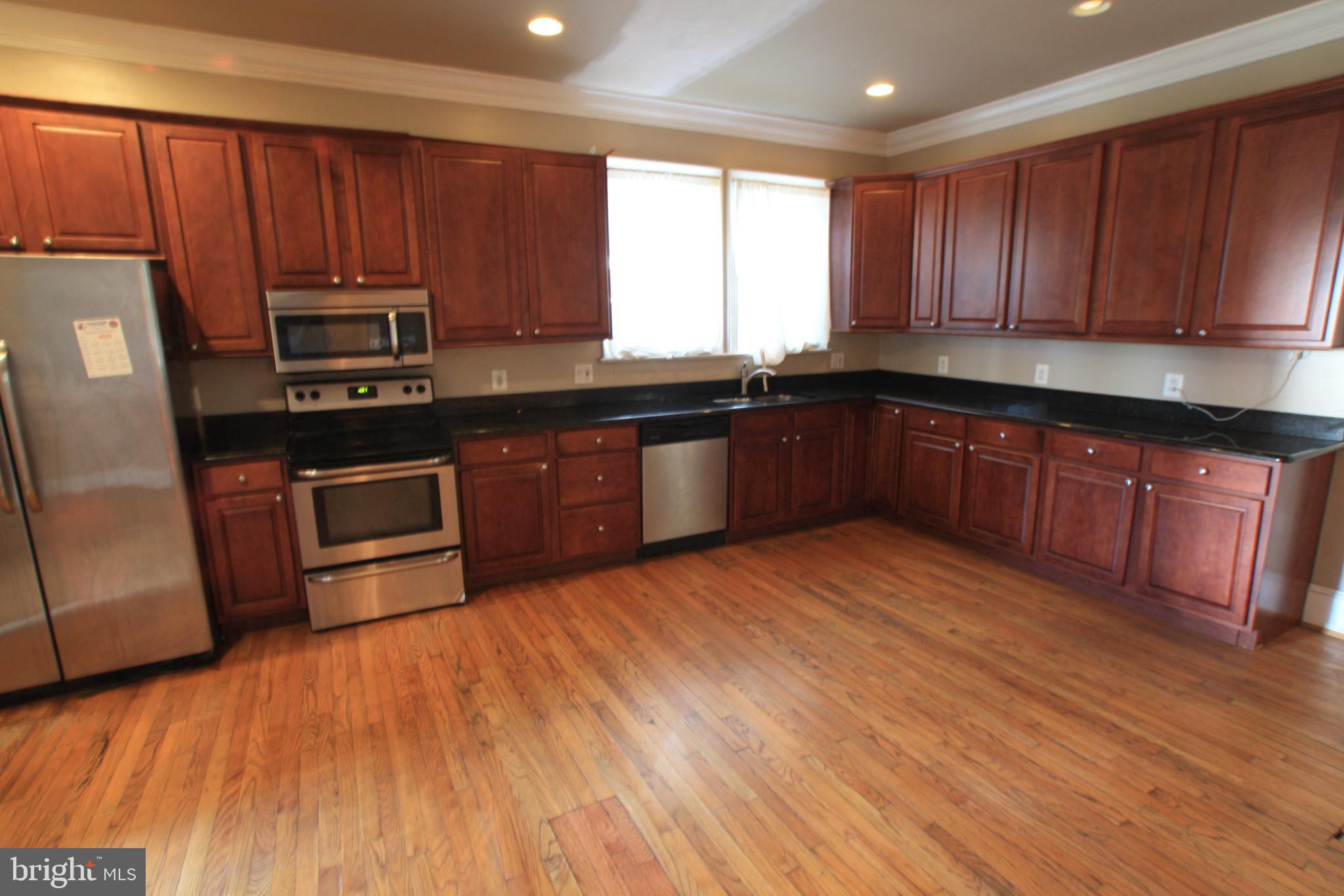1119 45th Street Northeast Washington, DC 20019 - Photo 10 of 24 a kitchen with stainless steel appliances granite countertop wooden floors and wooden cabinets