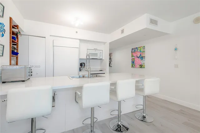 a white kitchen with a sink cabinets and wooden floor
