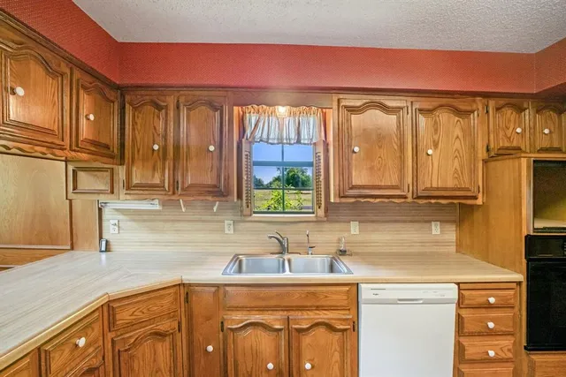 a kitchen with stainless steel appliances granite countertop a refrigerator a oven and white cabinets with wooden floors