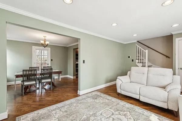 a living room with furniture and a dining table with wooden floor