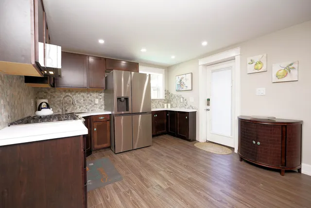 a kitchen with stainless steel appliances kitchen island granite countertop a refrigerator a sink dishwasher and a stove with wooden floor