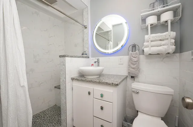a bathroom with a granite countertop toilet sink and mirror