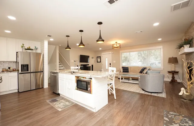 a kitchen with a refrigerator a stove top oven a sink dishwasher and white cabinets with wooden floor