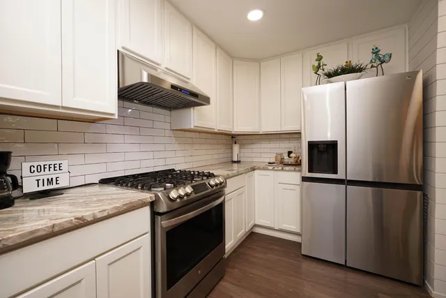 a kitchen with granite countertop a refrigerator stove and sink
