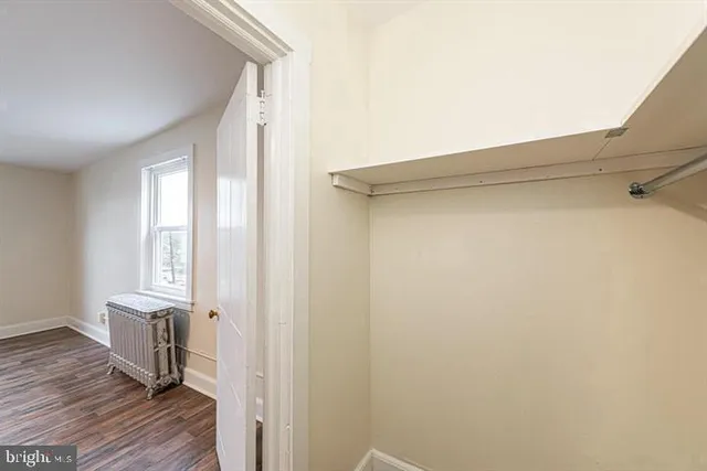 a view of a hallway with wooden floor and closet