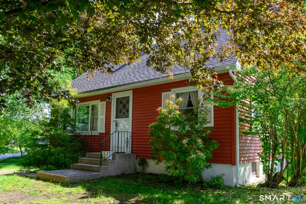 a view of a house with a yard plants and large tree