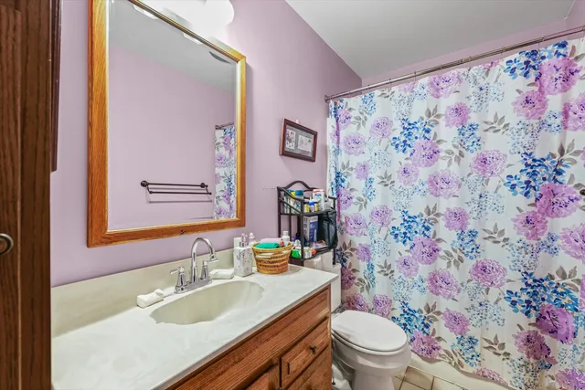 a bathroom with a granite countertop sink a toilet a shower and a mirror