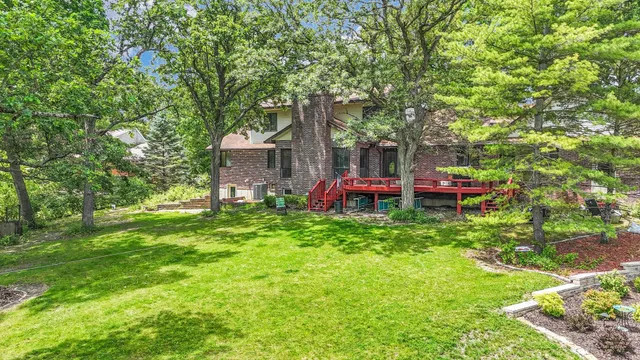 an aerial view of a residential houses with outdoor space and trees all around