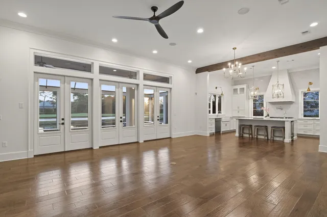 a view of an empty room with wooden floor and a large window