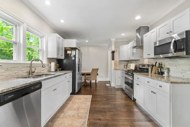 a kitchen with stainless steel appliances granite countertop refrigerator a sink a stove top oven with a dining table and chairs