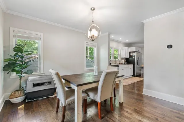 a dining room with wooden floor a chandelier a wooden table and chairs