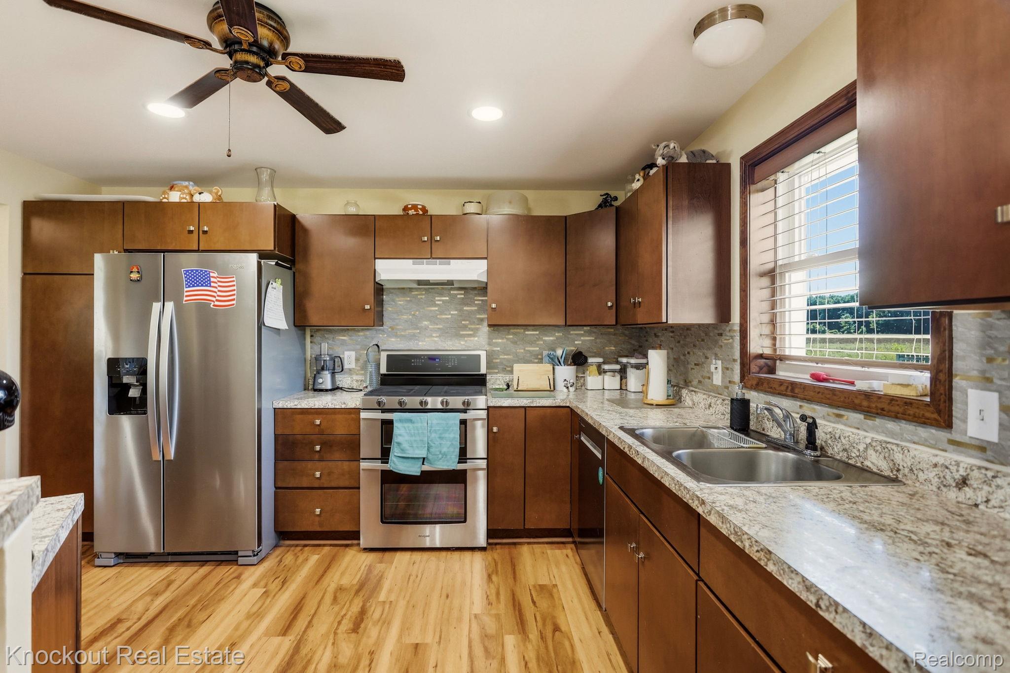 5727 Mackinaw Road Saginaw, MI 48604 - Photo 18 of 60 Kitchen featuring wood-finish flooring, stainless steel appliances, granite countertops, and wood cabinetry