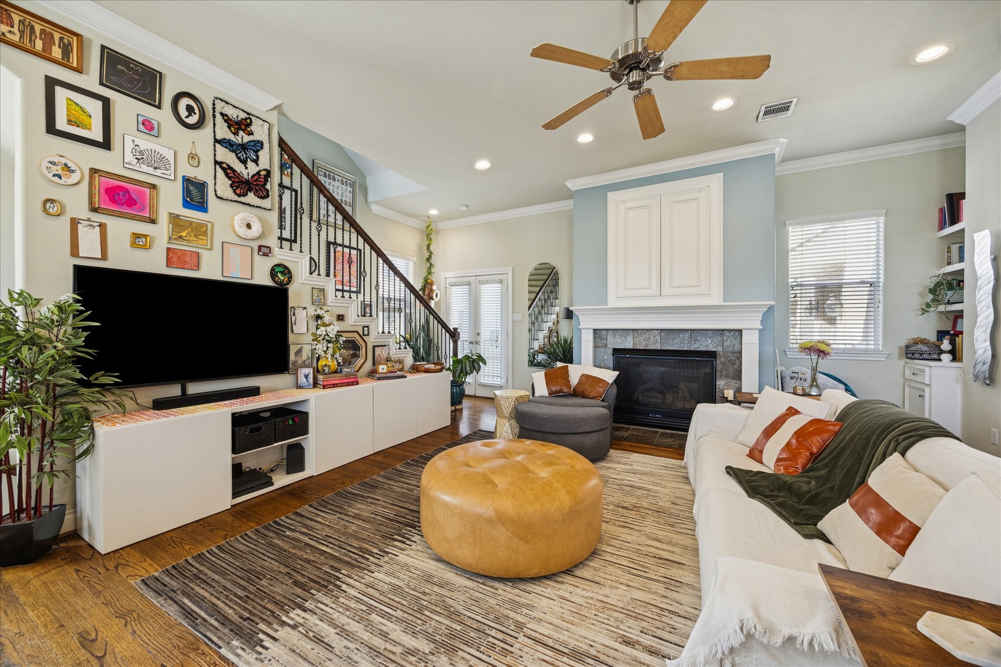 2207 Austin Street Houston, TX 77002 - Photo 2 of 34 The stairs leading up to the living room are just behid the plant by the TV. Beautiful solid oak flooring, high ceilings, gas log fireplace, windows, windows, windows. The stairs you can see lead up to the 3rd and 4th floors. The powder room is to the far back right of this picture. And you can see the french doors leading out to the balcony.