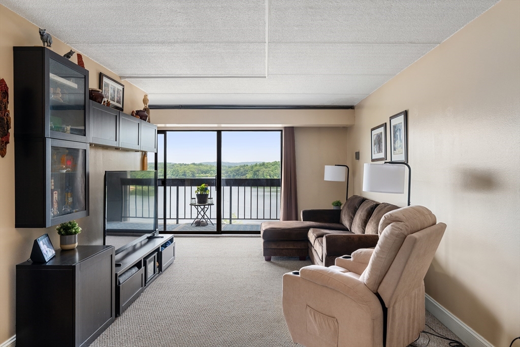 1500 Worcester Road, Unit 624 Framingham, MA 01702 - Photo 6 of 26 a living room with furniture floor to ceiling window and a flat screen tv
