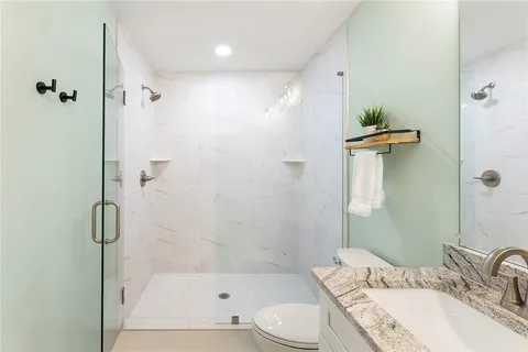a bathroom with a granite countertop sink toilet and shower