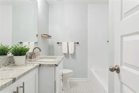 a bathroom with a granite countertop sink a toilet and shower